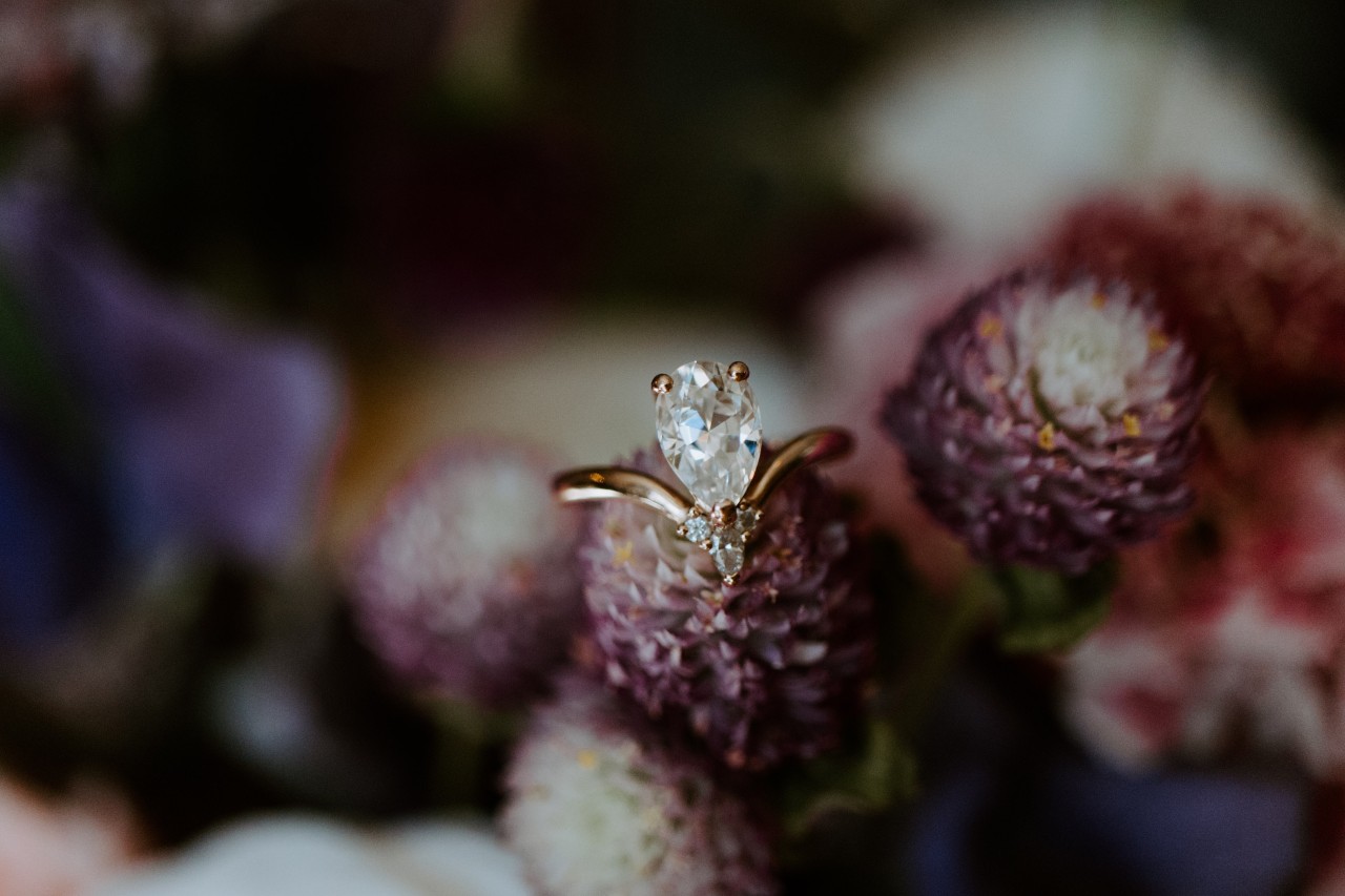A contemporary engagement ring sits on an unconventional flower bouquet.