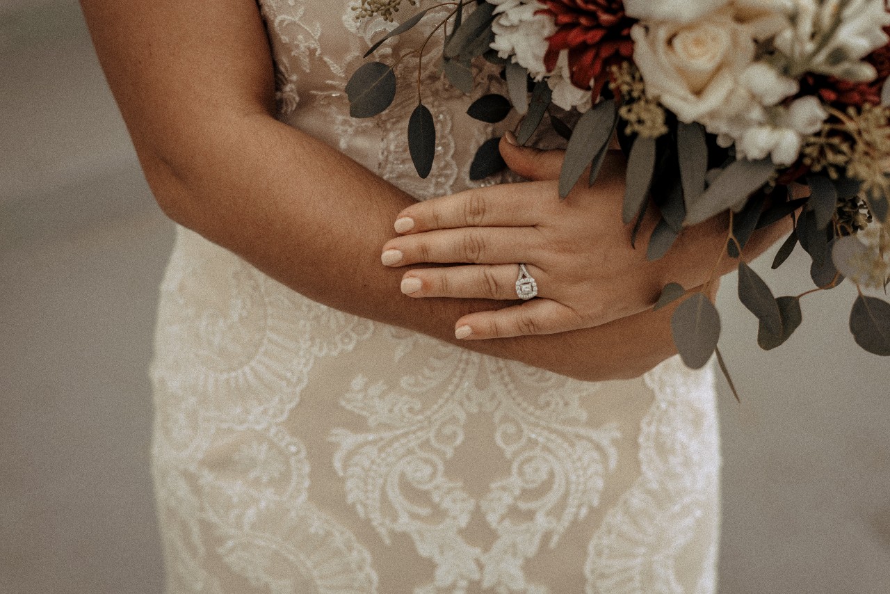 A bride hugs her bouquet while showing her modern halo ring.