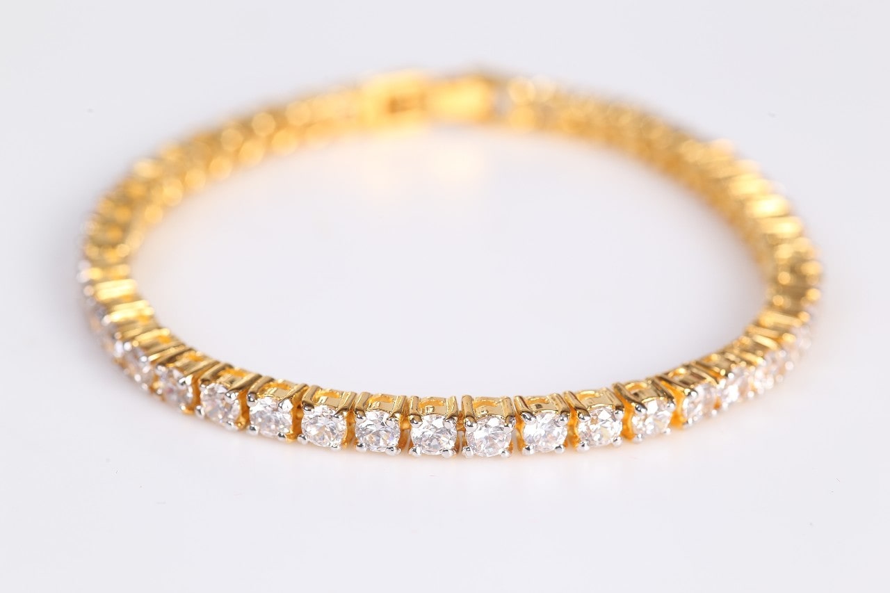 A gold diamond tennis bracelet on a white background