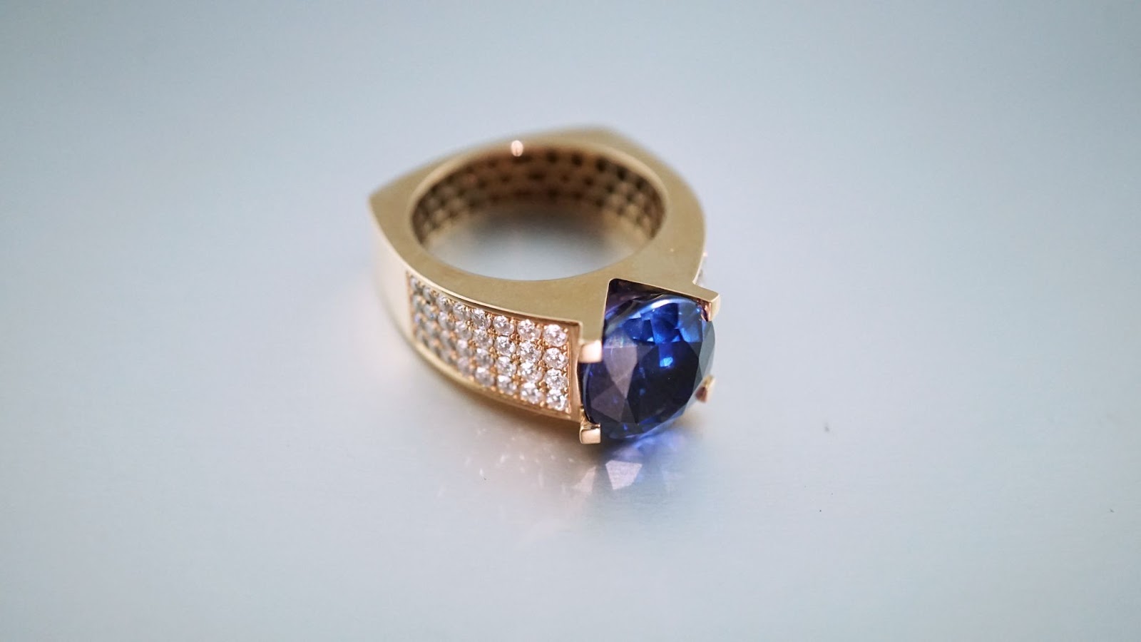 A yellow gold ring with a large sapphire and accented with diamond side stones