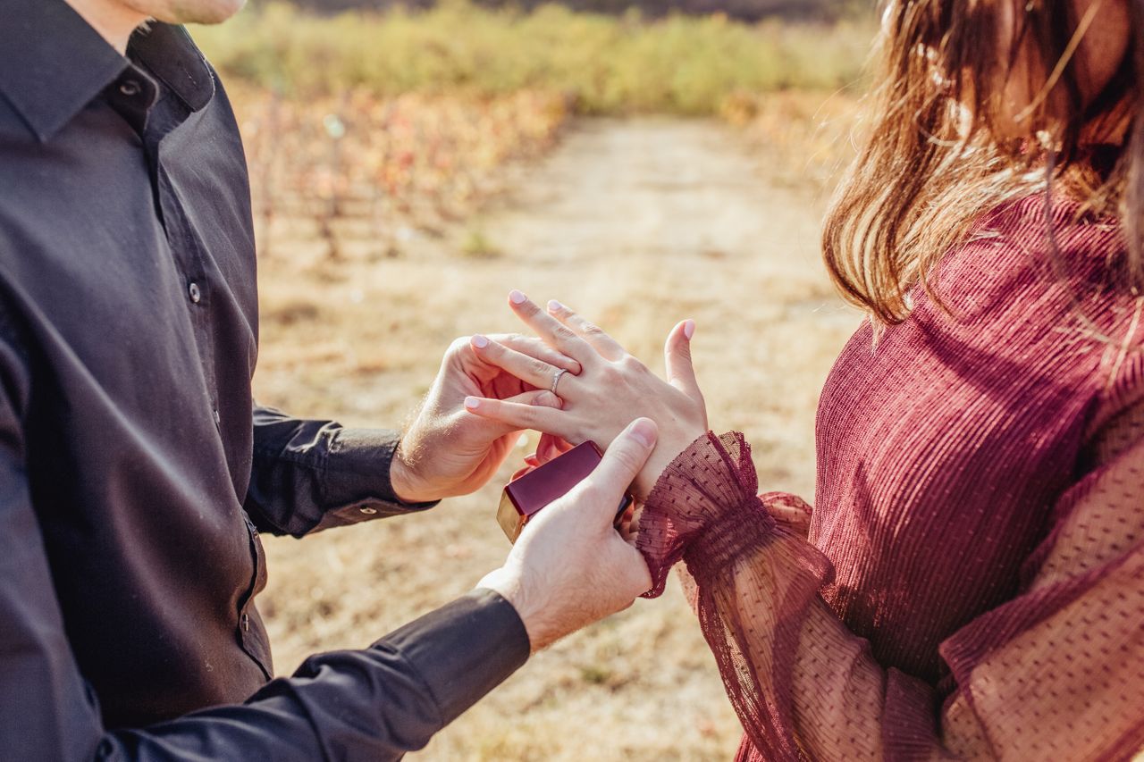 man slipping an engagement ring on a woman’s finger