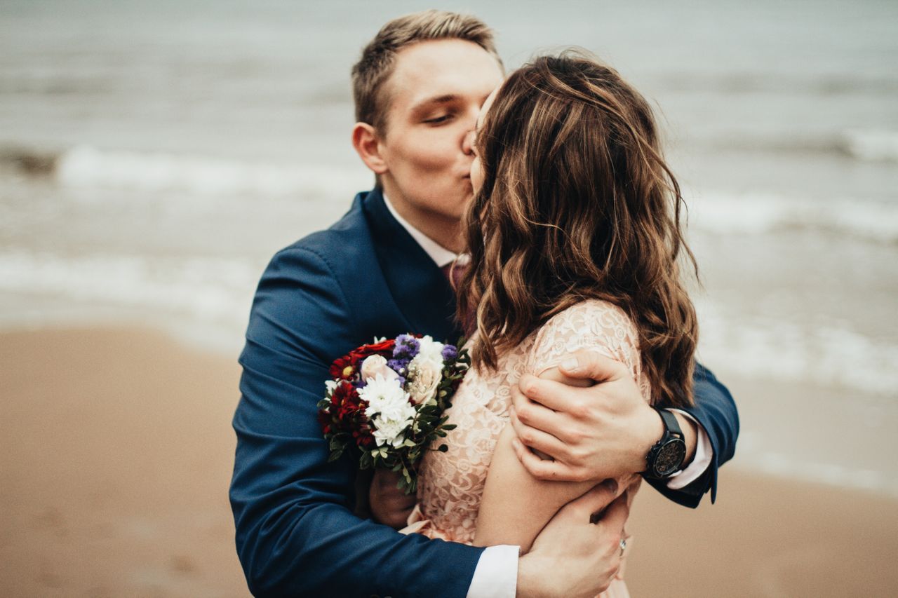 bride and groom kissing on a beach