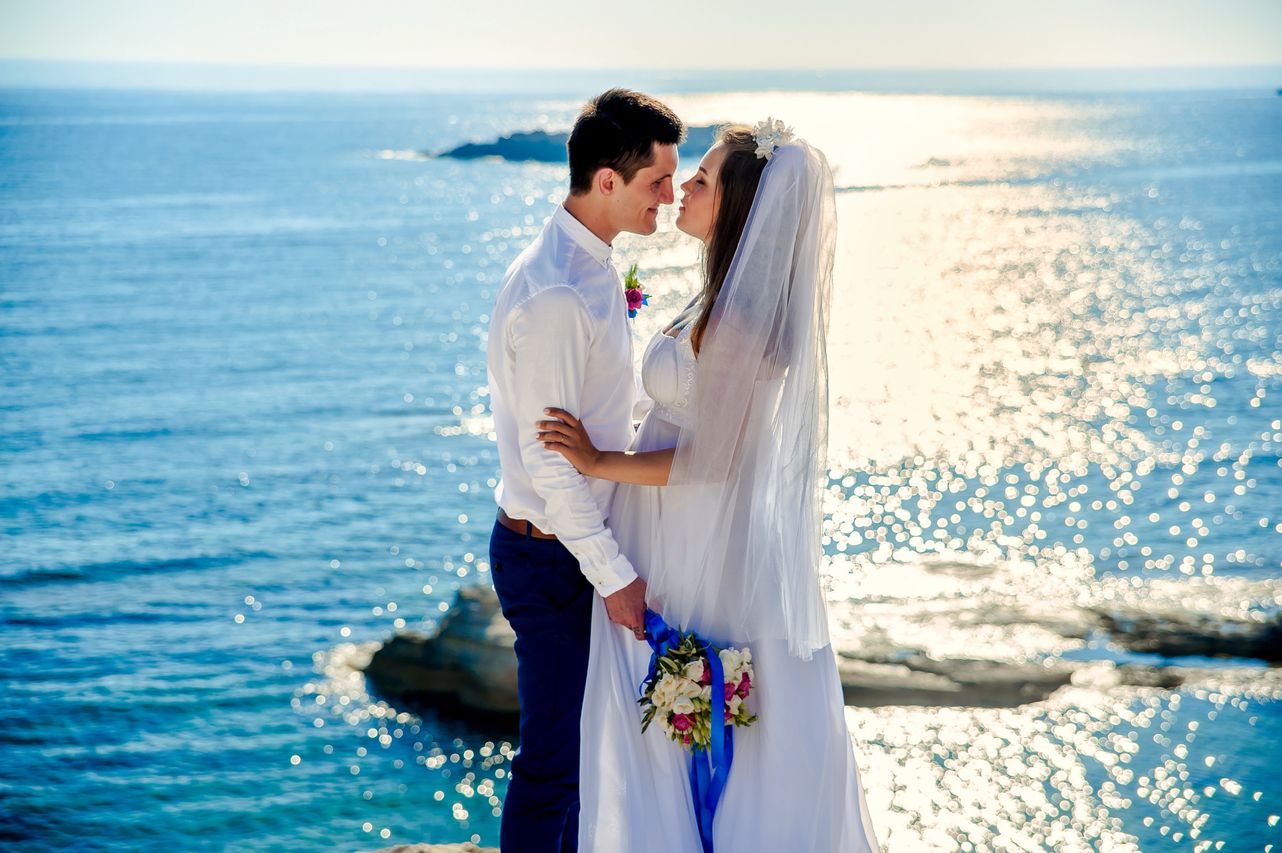 bride and groom embracing in front of a body of water