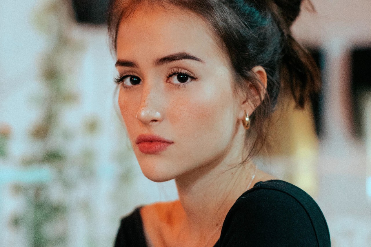 a woman wearing a messy bun and gold hoop earrings in a cafe.