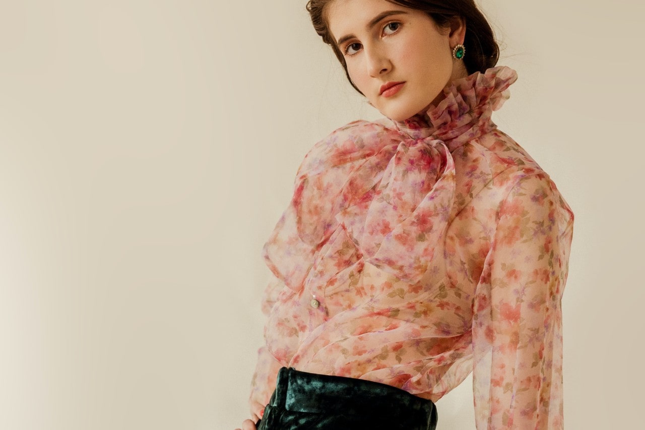 woman in a floral blouse and a pair of large green gemstone stud earrings