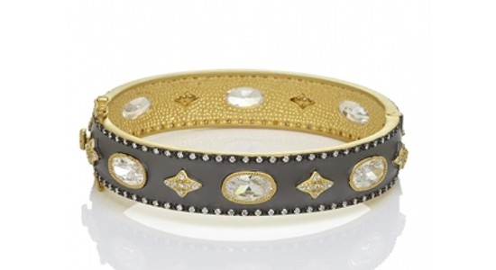 a chunky gray bangle with gold details and clear gems