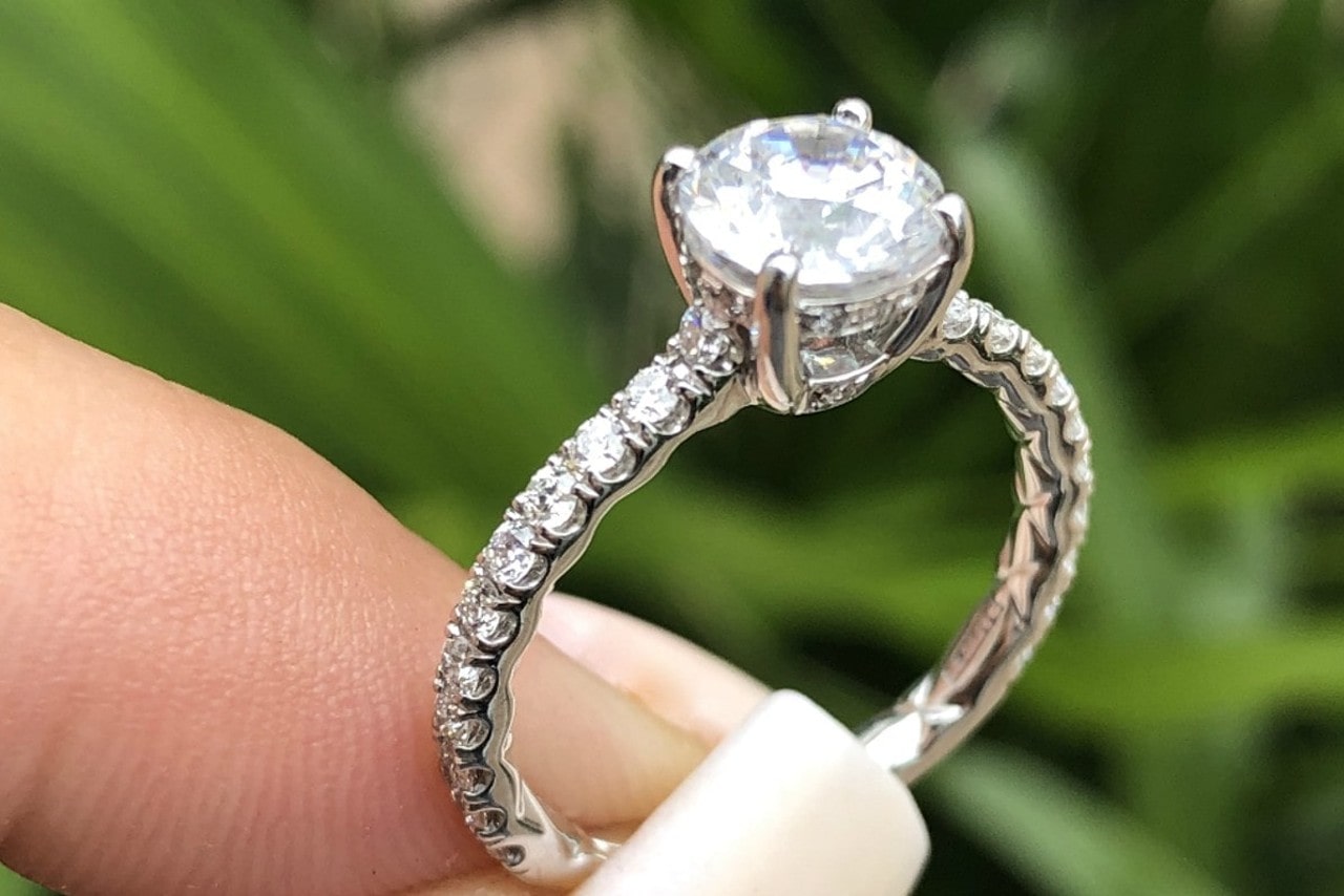 a woman hold a side-stone engagement ring with a round cut diamond.