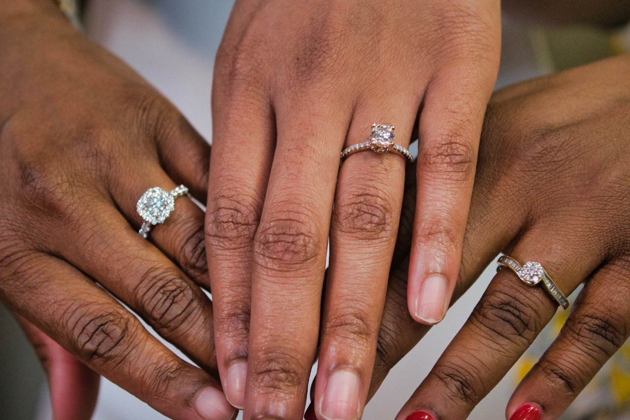 A group of women show off their engagement rings, each featuring different styles.