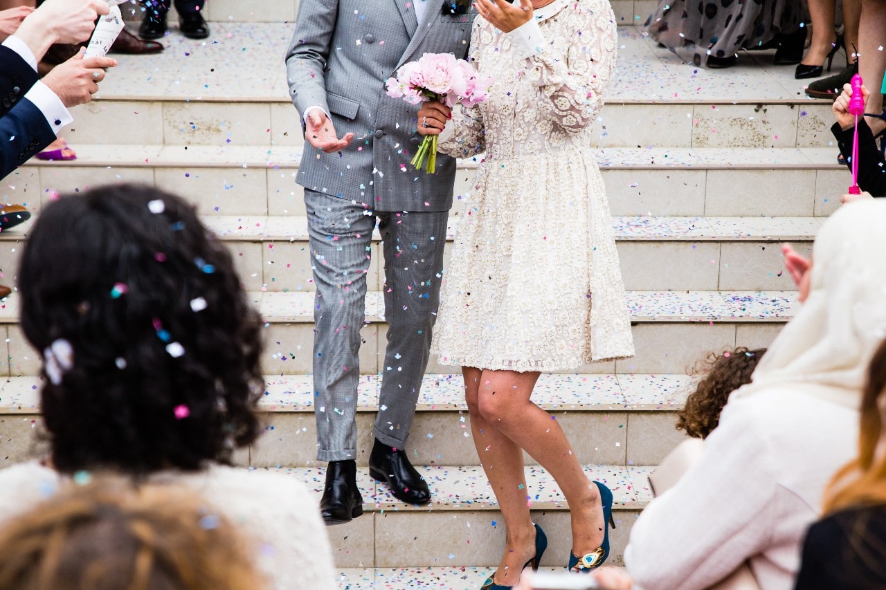 Guests throw confetti as a newly-married couple exits their ceremony.